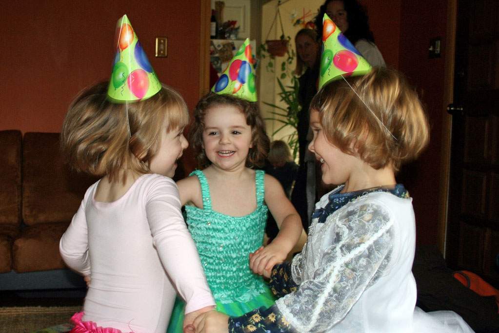 three children with party hats on holding hands