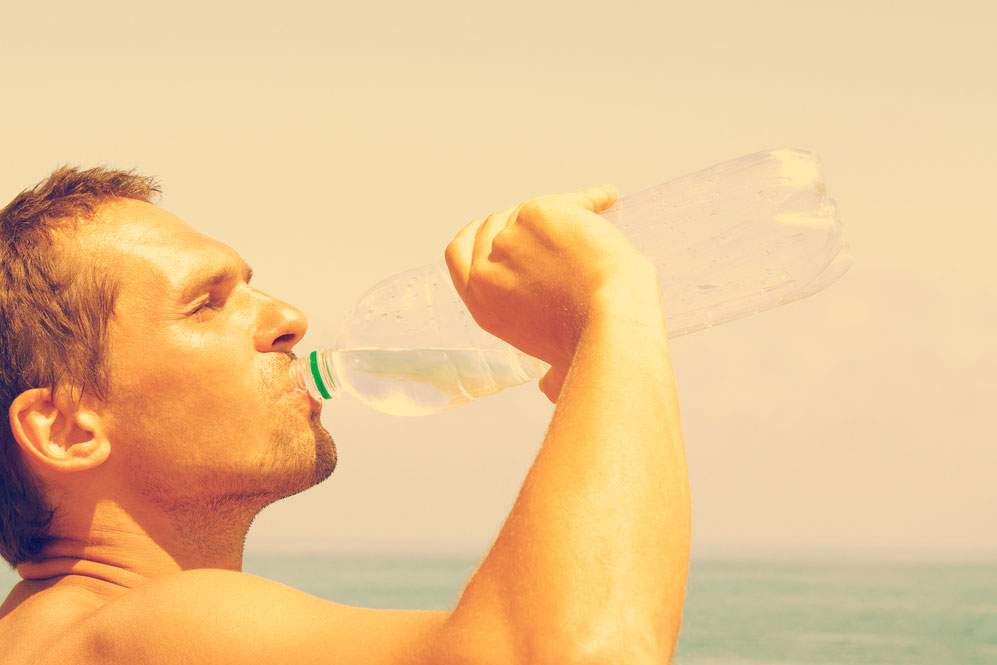 Man drinks bottled water near waterfront