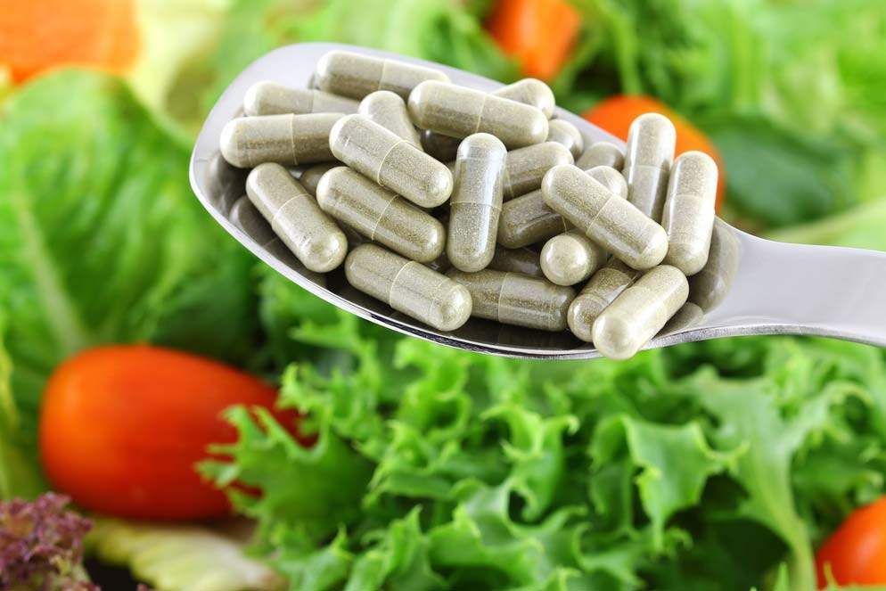 antioxidant capsules in focus, salad out of focus