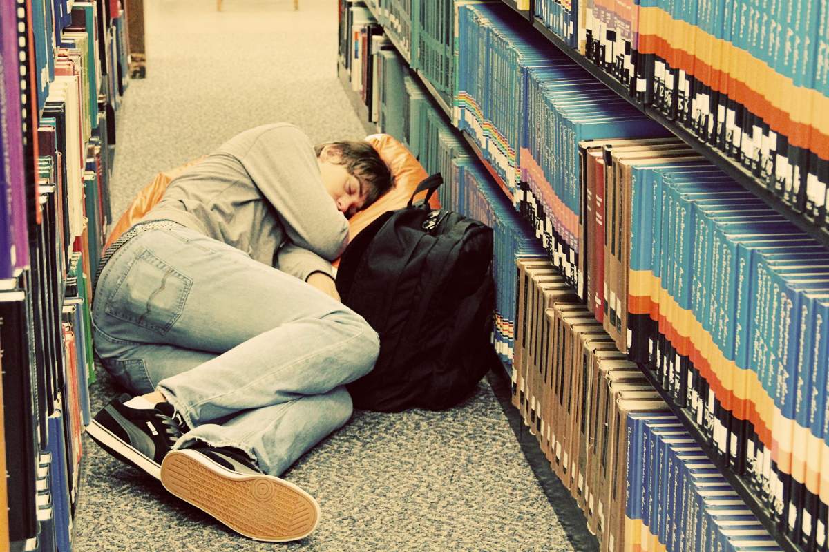 student sleeping in library stacks