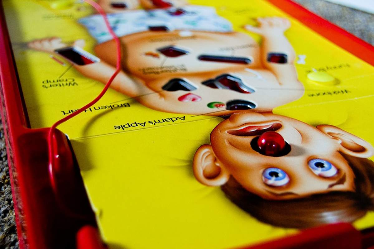 A close-up on the board game Operation. The game has an image of a man on a yellow background.