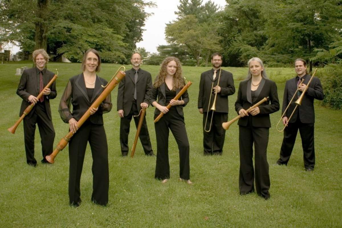 musicians standing in a meadow with instruments