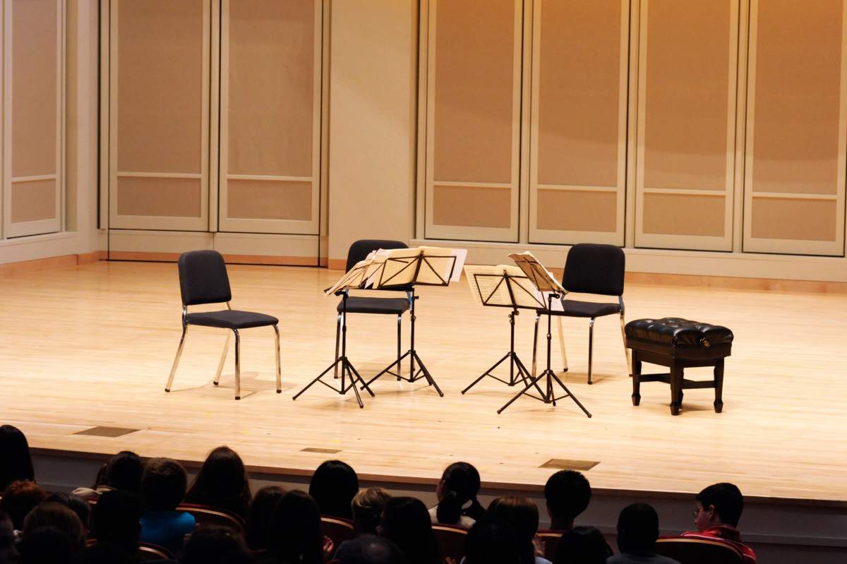 Three chairs, a bench and four music stands on a stage