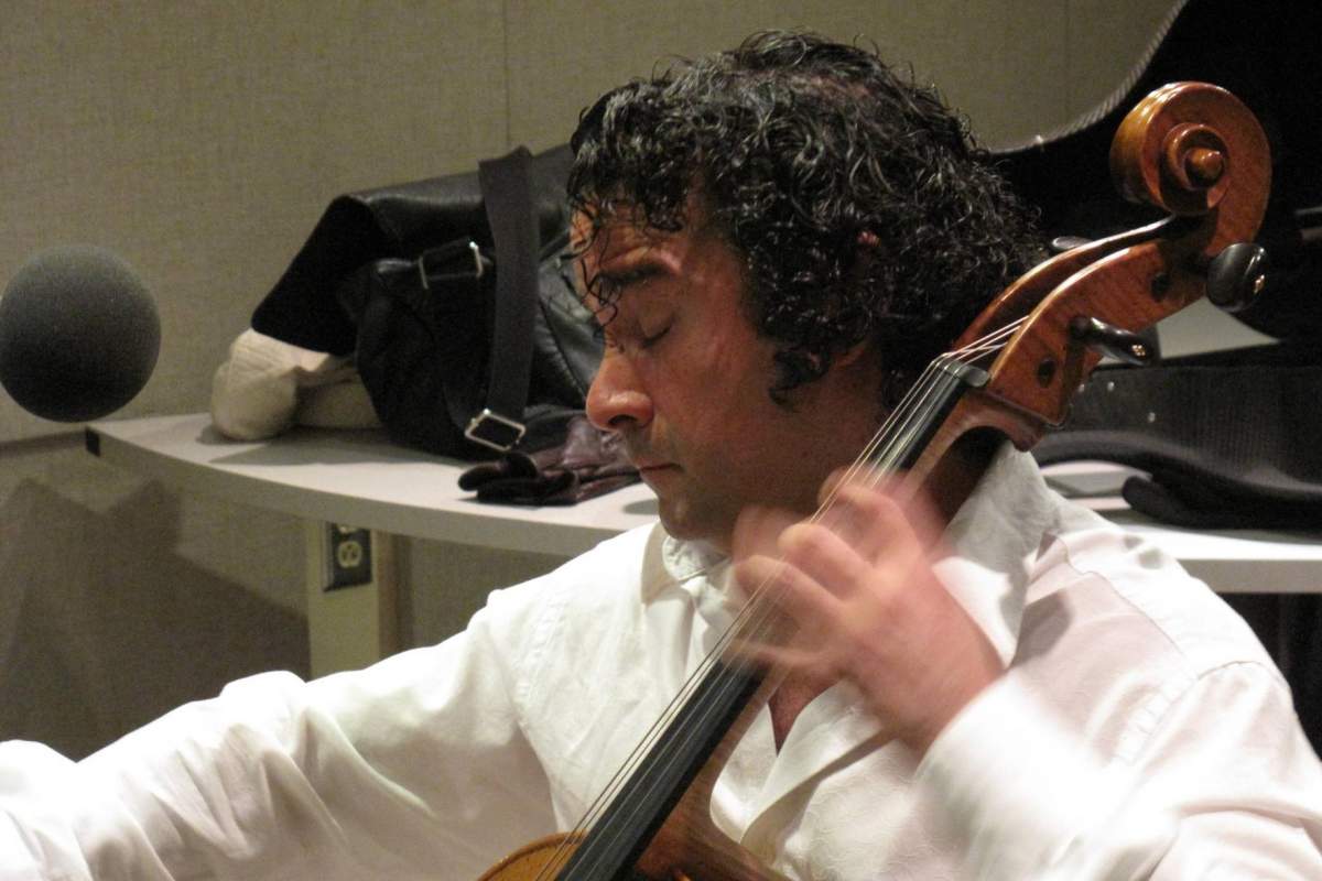 a man sits playing a cello