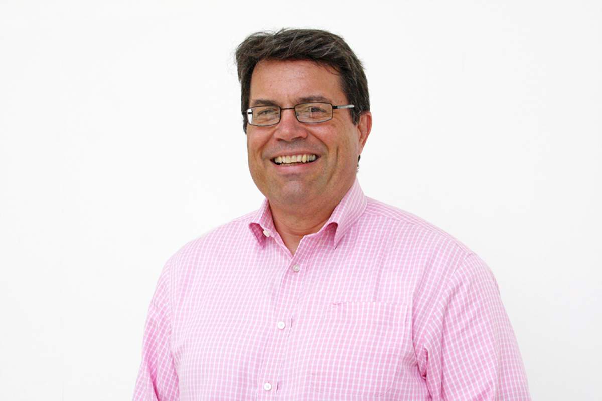 David Brenneman, smiling broadly, wearing glasses and pink oxford shirt