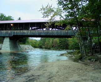 The open sides of the Saco River Bridge allow the structure's arches to be seen from the river bank.