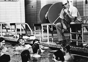 Doc muses poolside, while swimmers laugh in the water.