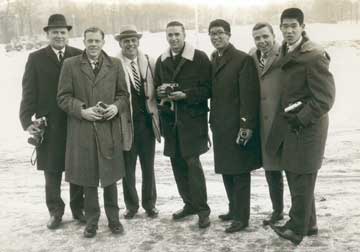 Doc poses for a wintertime portrait with a group of students, cameras in hand.