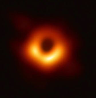 An image of the black hole at the center of the Milky Way galaxy, a dark mass in the center of a hazy orange halo