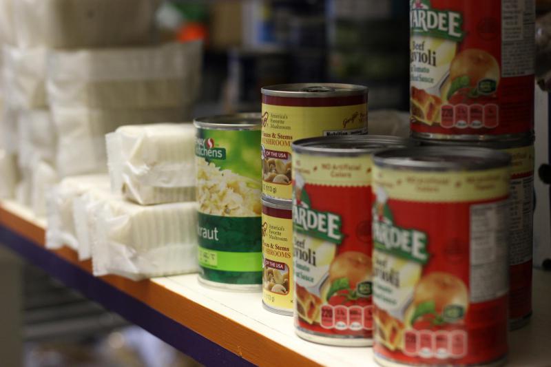 Close-up of canned foods and sleeves of saltine crackers on a shelf.