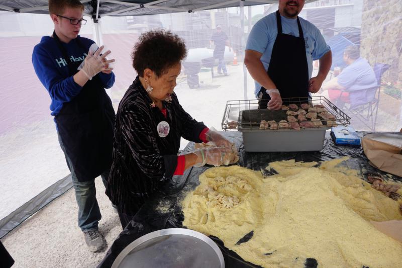 People preparing fish in an outdoor tent