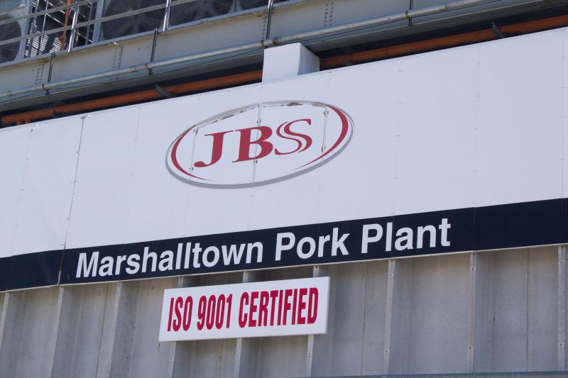 White sign with red and black letters saying "JBS Marshalltown Pork Plant"