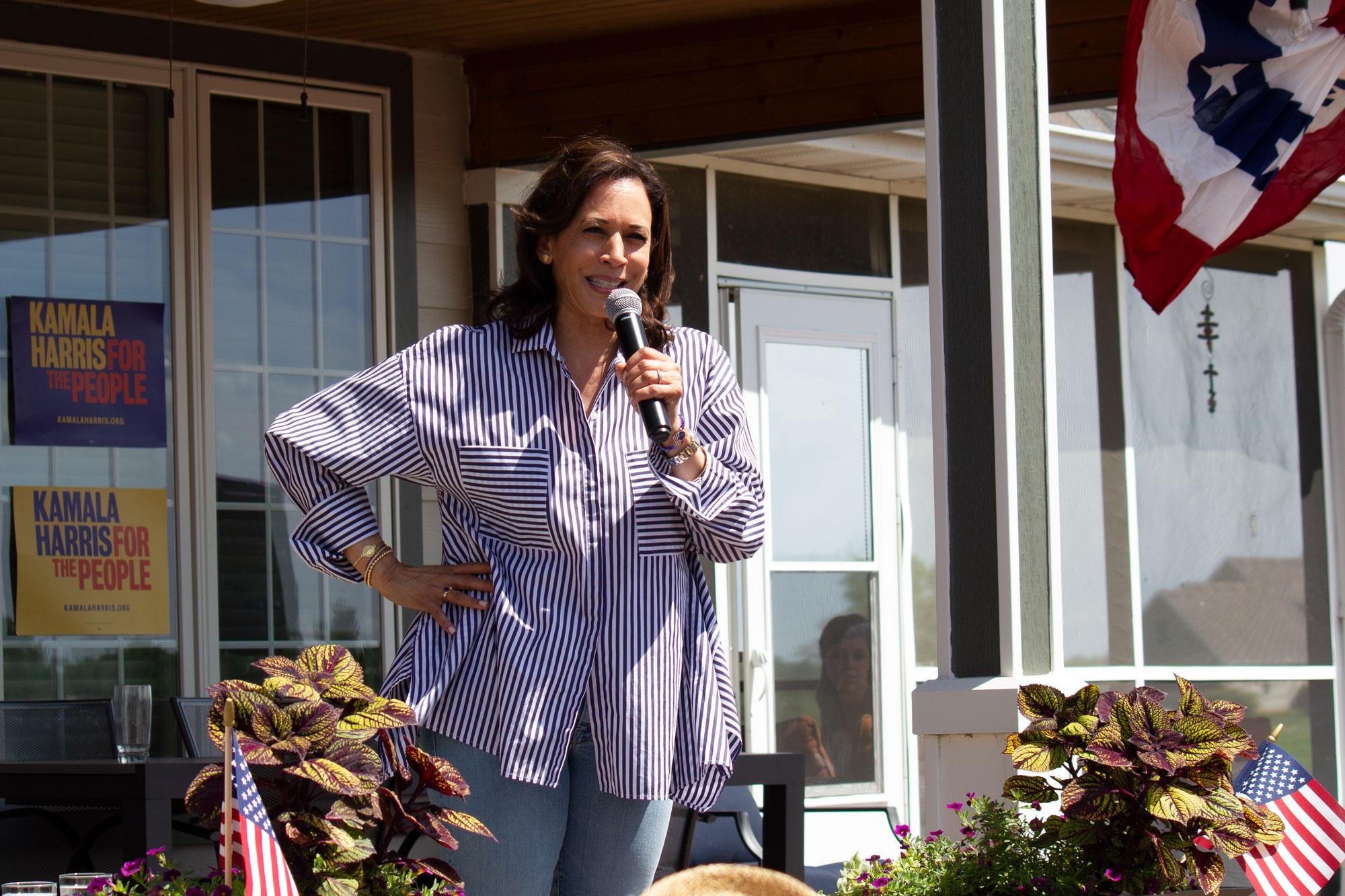 Kamala Harris with microphone in hand in front of a home in Iowa. 