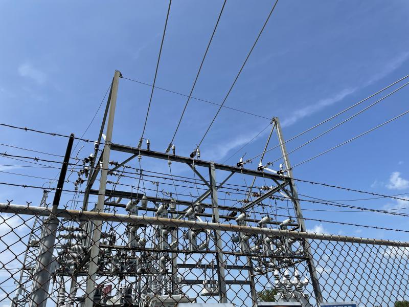 The top of an electrical transformer with blue sky in the bacgkground