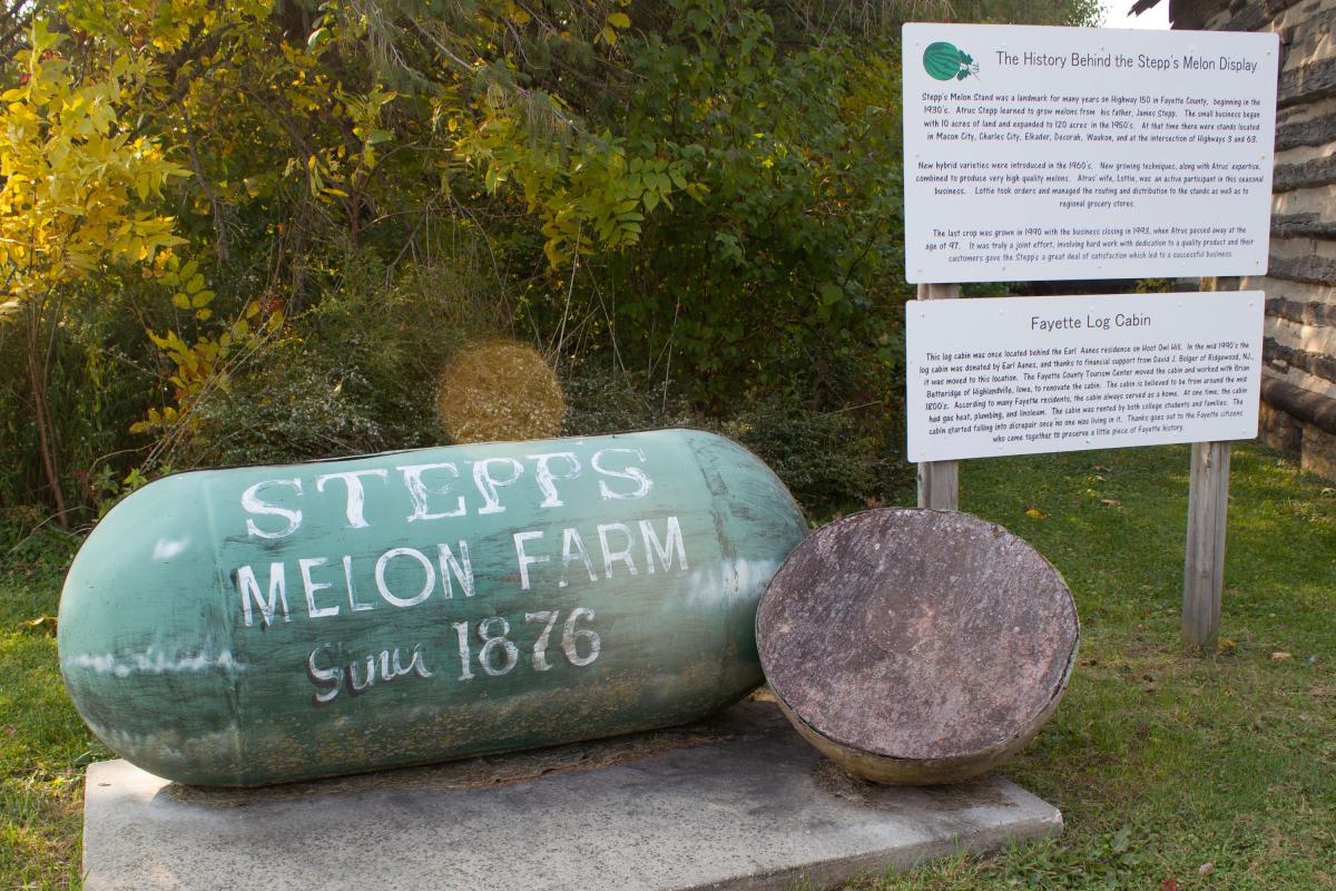 An old propane tank on a concrete pad with faded paint saying "Stepp's Melon Farm since 1876"