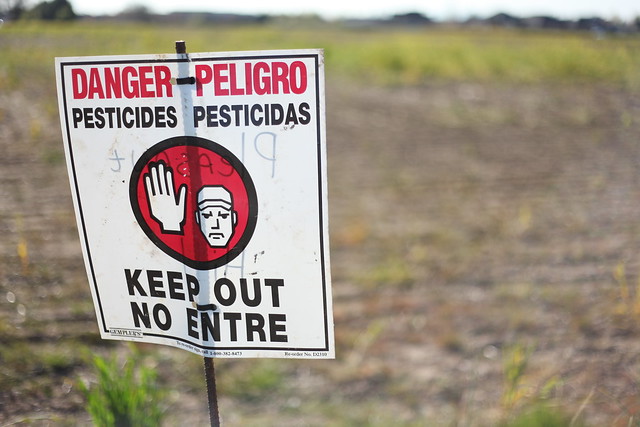 A close-up of a pesticide warning sign in a field.