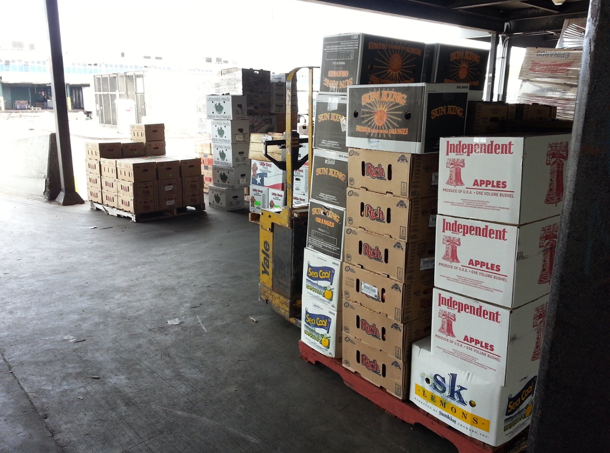 Boxes of produce stacked in a warehouse at a dock or opening to the building