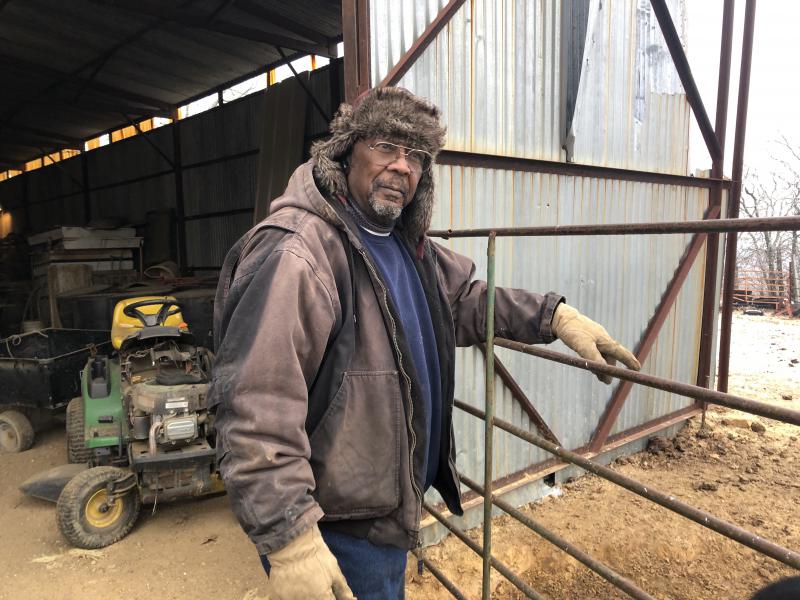 Alvin Lee standing at a gate next to a metal barn, in winter gear.