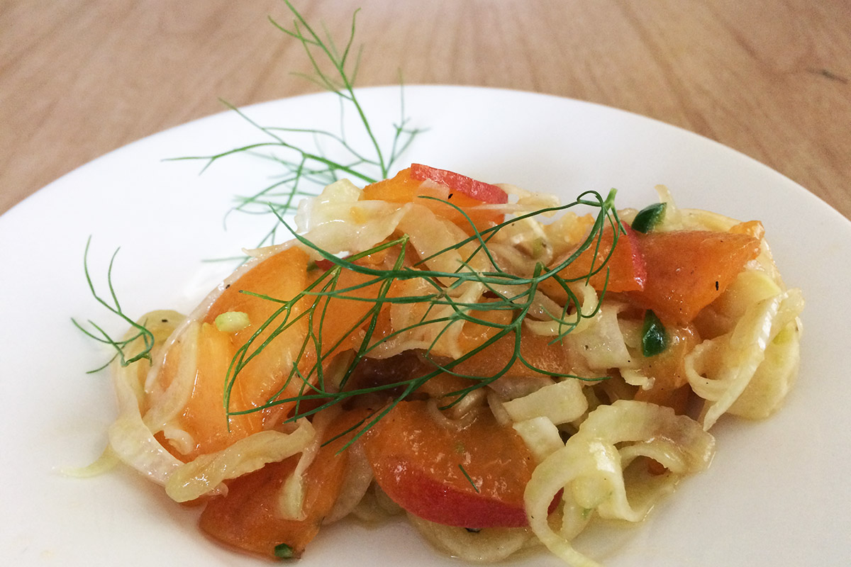 apricot and fennel salad on a white plate with fennel frond garnish