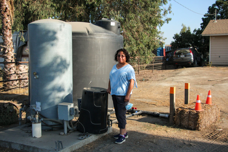 Esther Espinoza standing next to her water tank 