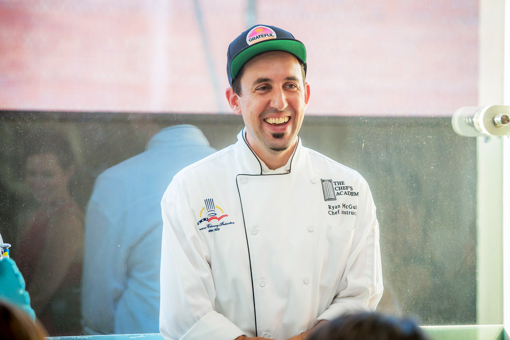 Ryan McGuire, a young white man in a chef's jacket and ballcap, smiling