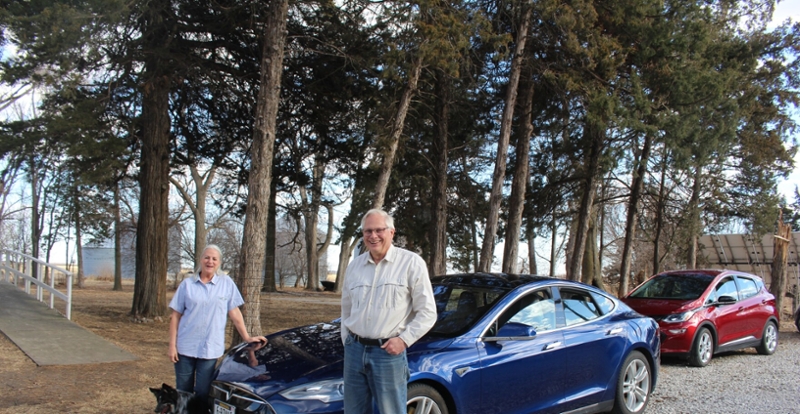 Alan and Nancy Meyer standing by their electic cars