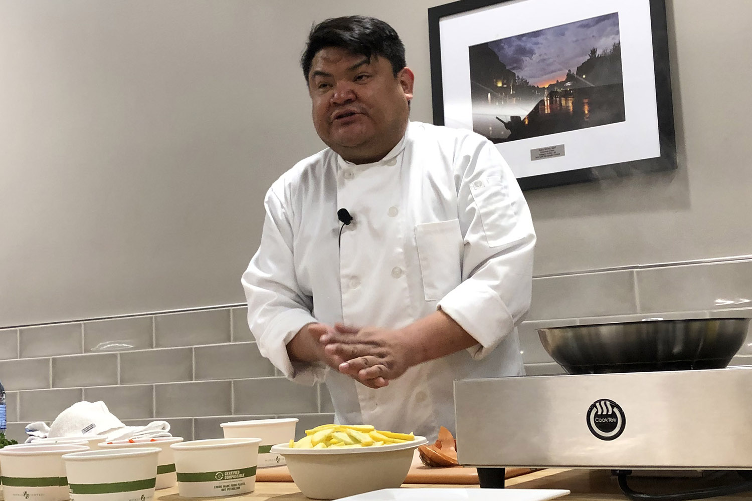 Chef Freddie Bitsoie standing in white chef's jacket at a table with bowls of food and an induction burner.