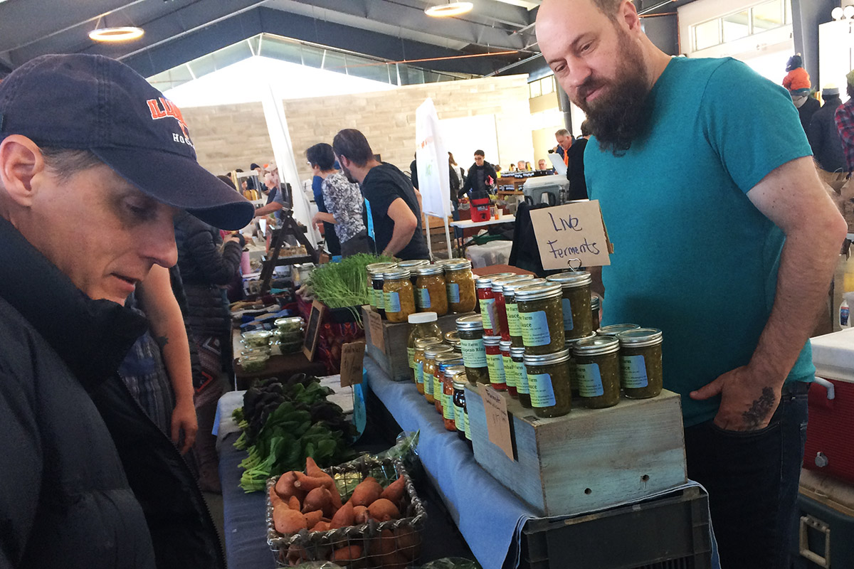 A farm stand, indoors, with customer and farmer