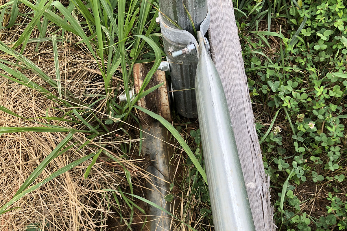 Close-up of rail and wheel for moveable high tunnels, with grass growing around it.