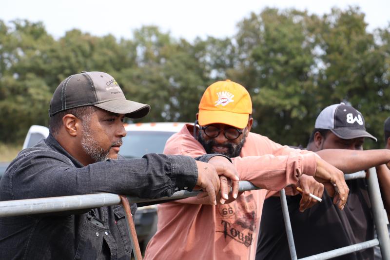 Nathan Bradford Jr. and Willard Tillman wearing ball caps and leaning their arms on a metal gate.