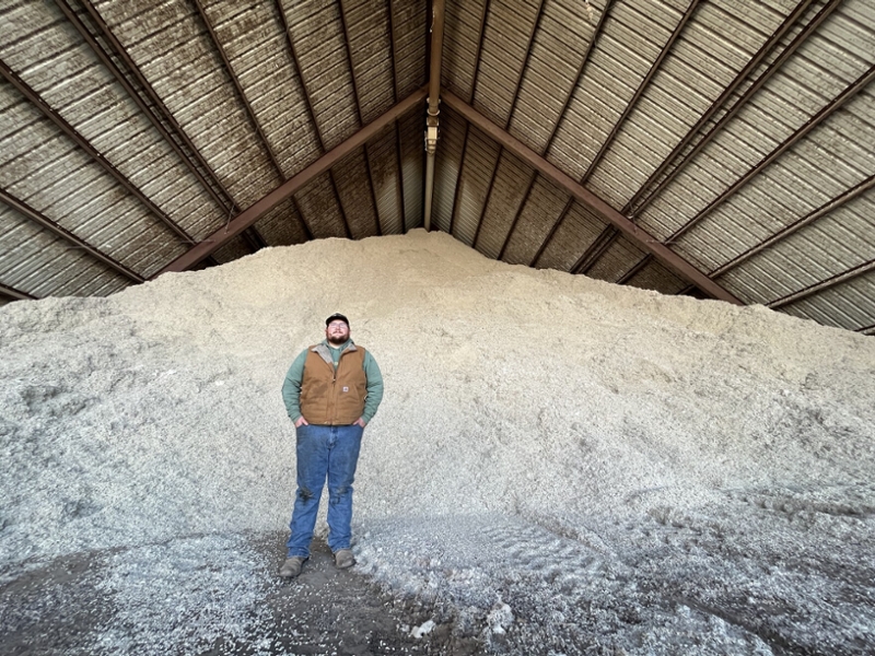 Michael Cutchins standing in front of a mountain of cottonseeds
