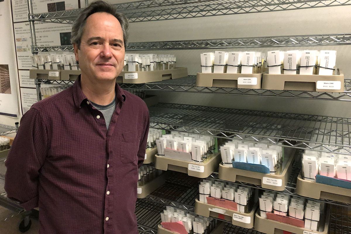 Kevin Cook standing in front of a rack full of trays of labled vials.