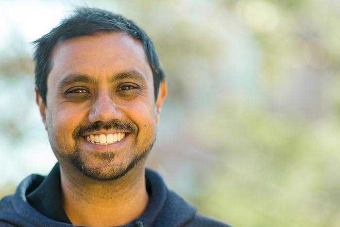 head shot of Pablo Bose smiling at camera with green blurred background