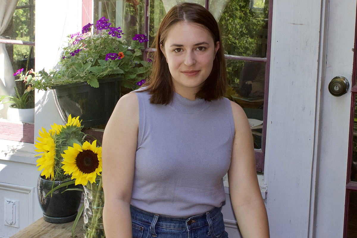 Melanie Tafejian outdoor in front of a window with flowers behind her