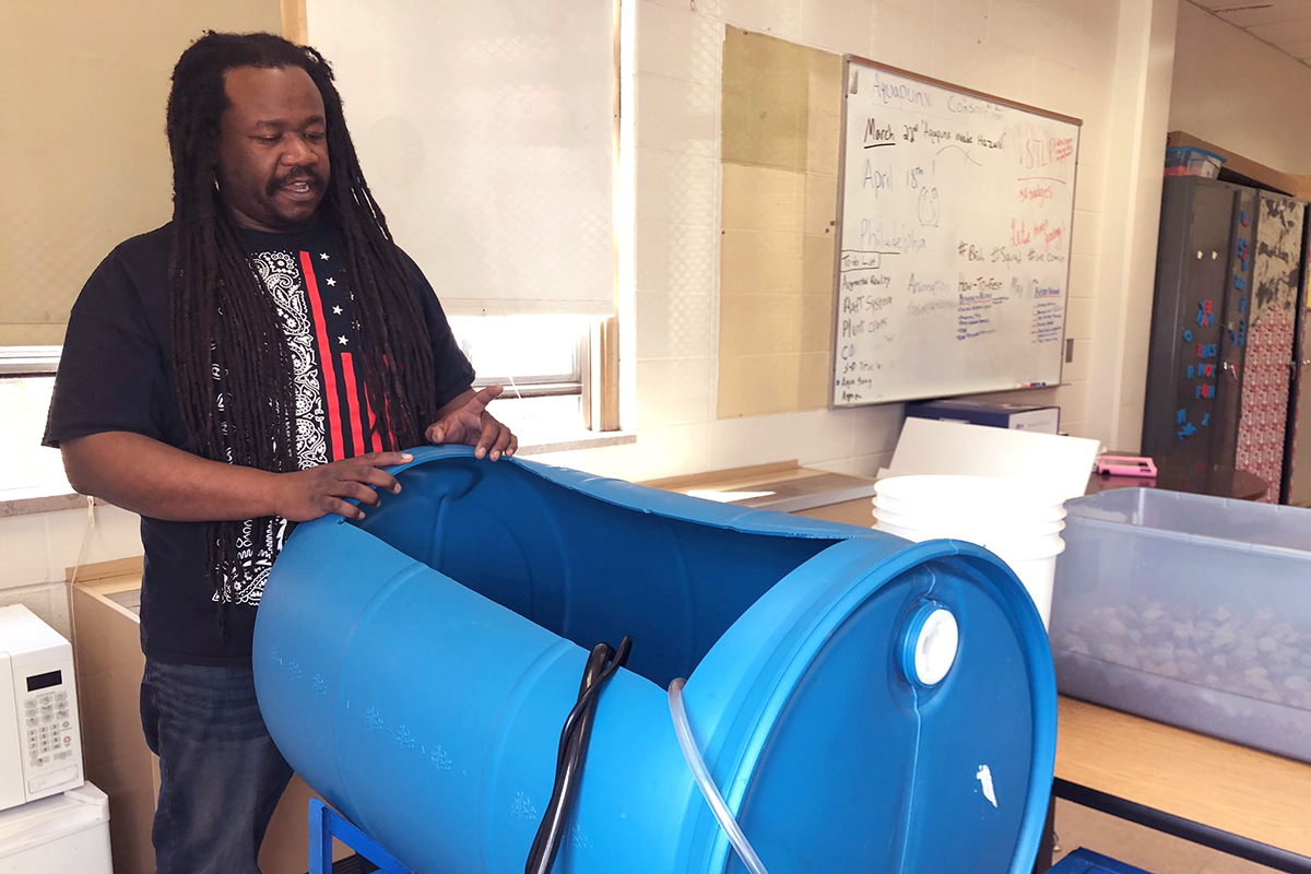 Michael George standing with a modified blue tank, talking