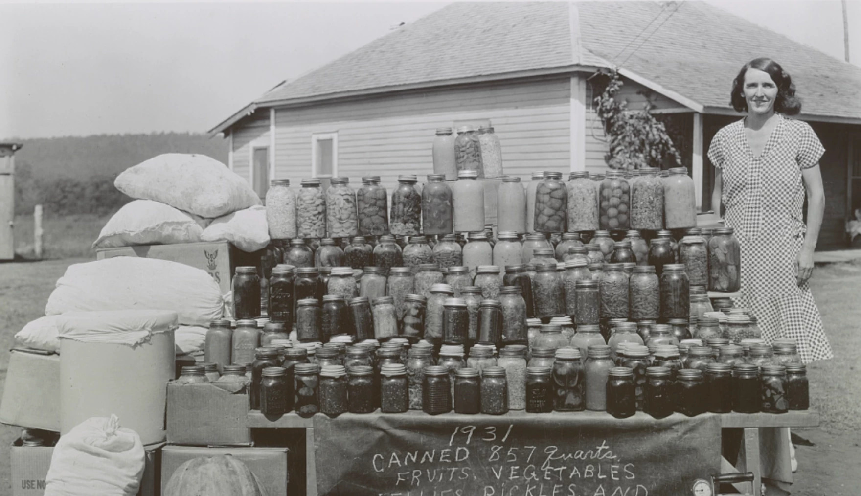 A black and white photo of a woman beside cans