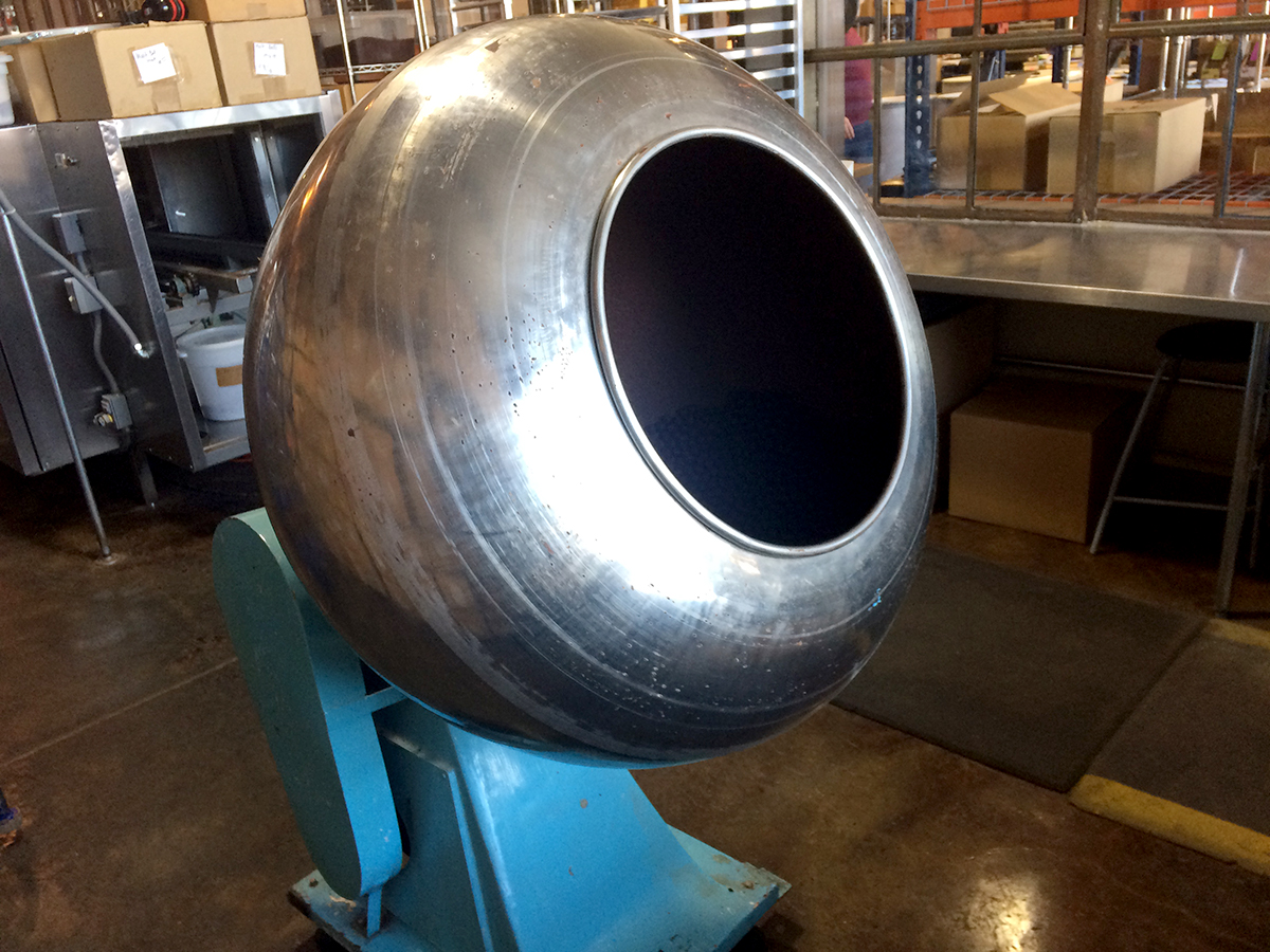 A big metal machine with a round steel barrel and a light blue base