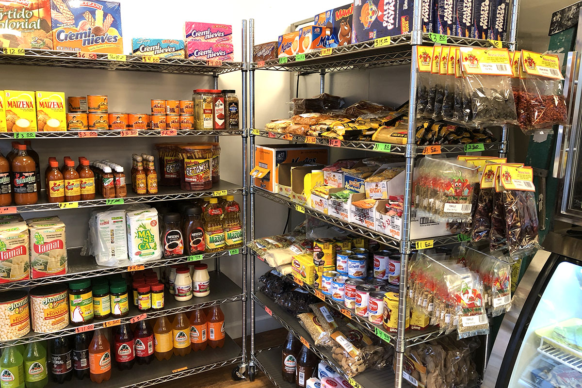 Metal grocery store shelves stocked with various colorful groceries from Mexico.