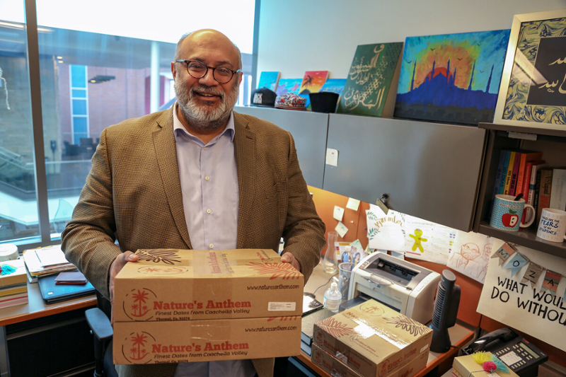 Omer Mozaffar, Loyola University Chicago's Muslim chaplain, holds boxes of dates in his office