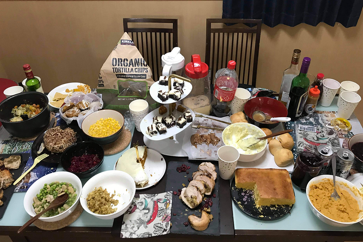 A table crowded with many different dishes of food and drink, partially consumed