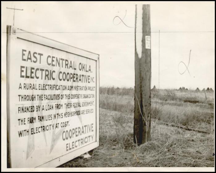 A sepia-toned old photograph of a sign for a rural electric cooperative in Oklahoma