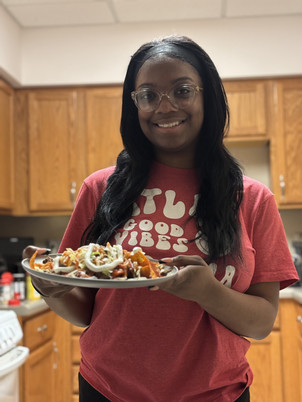MaKiya Tramil smiles and holds taco salad on a plate