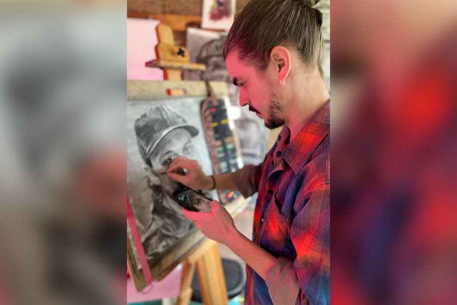Artist Michael Sinclair uses charcoal to draw a portrait.