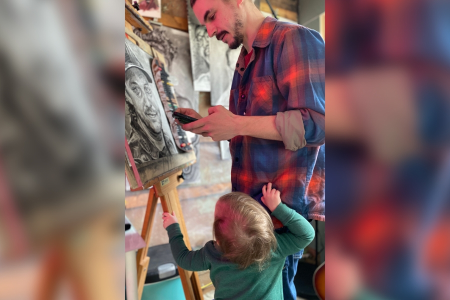 Artist Michael Sinclair works on a portrait alongside his son.