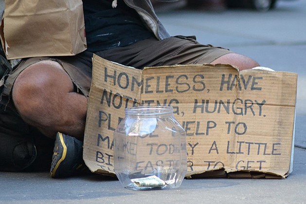 An image of a homeless man holding a sign.