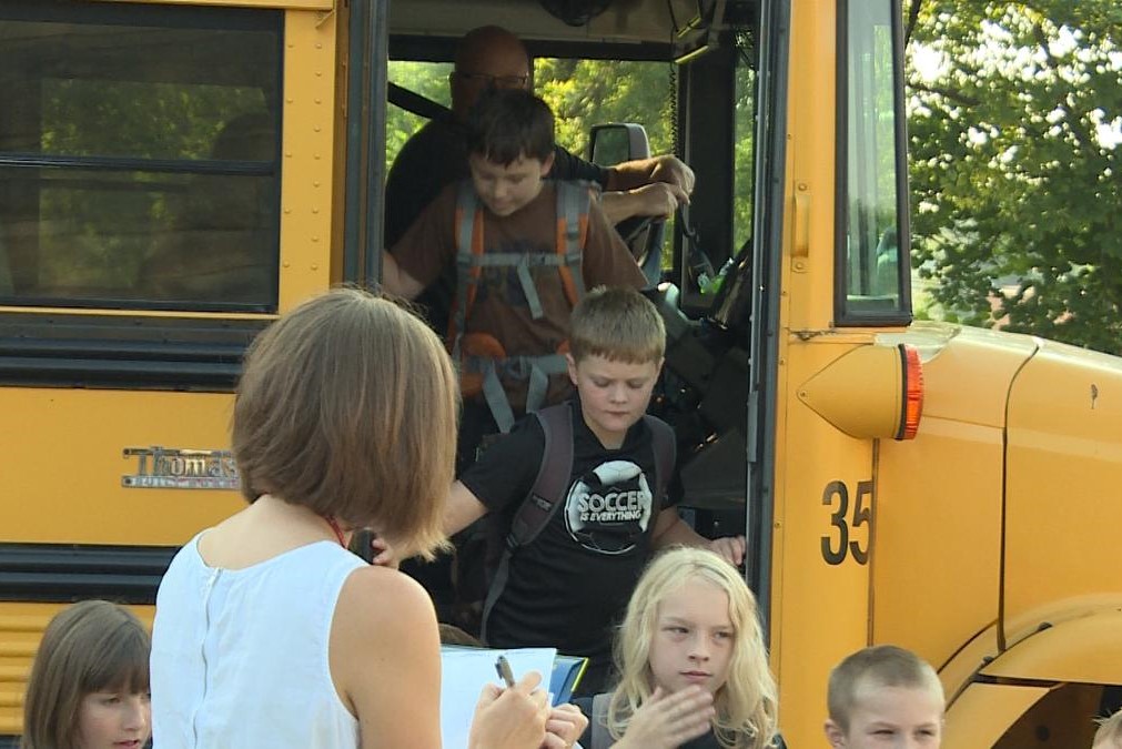 Kids get off of a school bus.