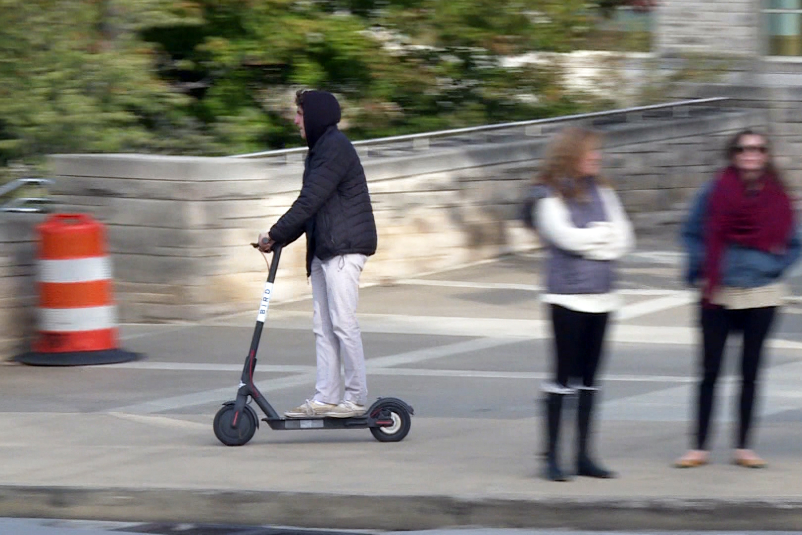 A student rides a Bird electric scooter through campus.