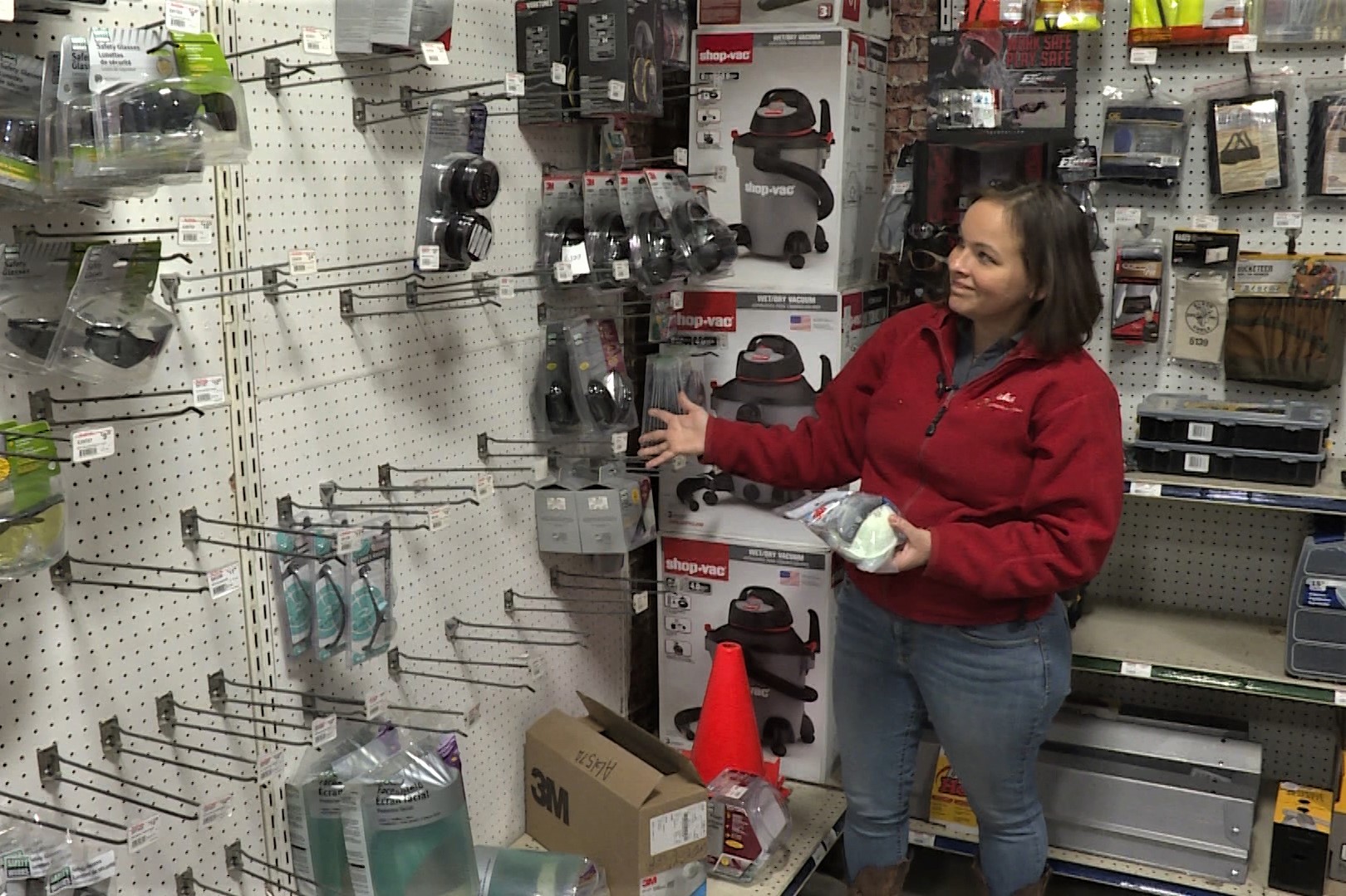 Bloomington Hardware manager Kristi Hill shows off empty racks where construction and respirator masks are usually displayed.