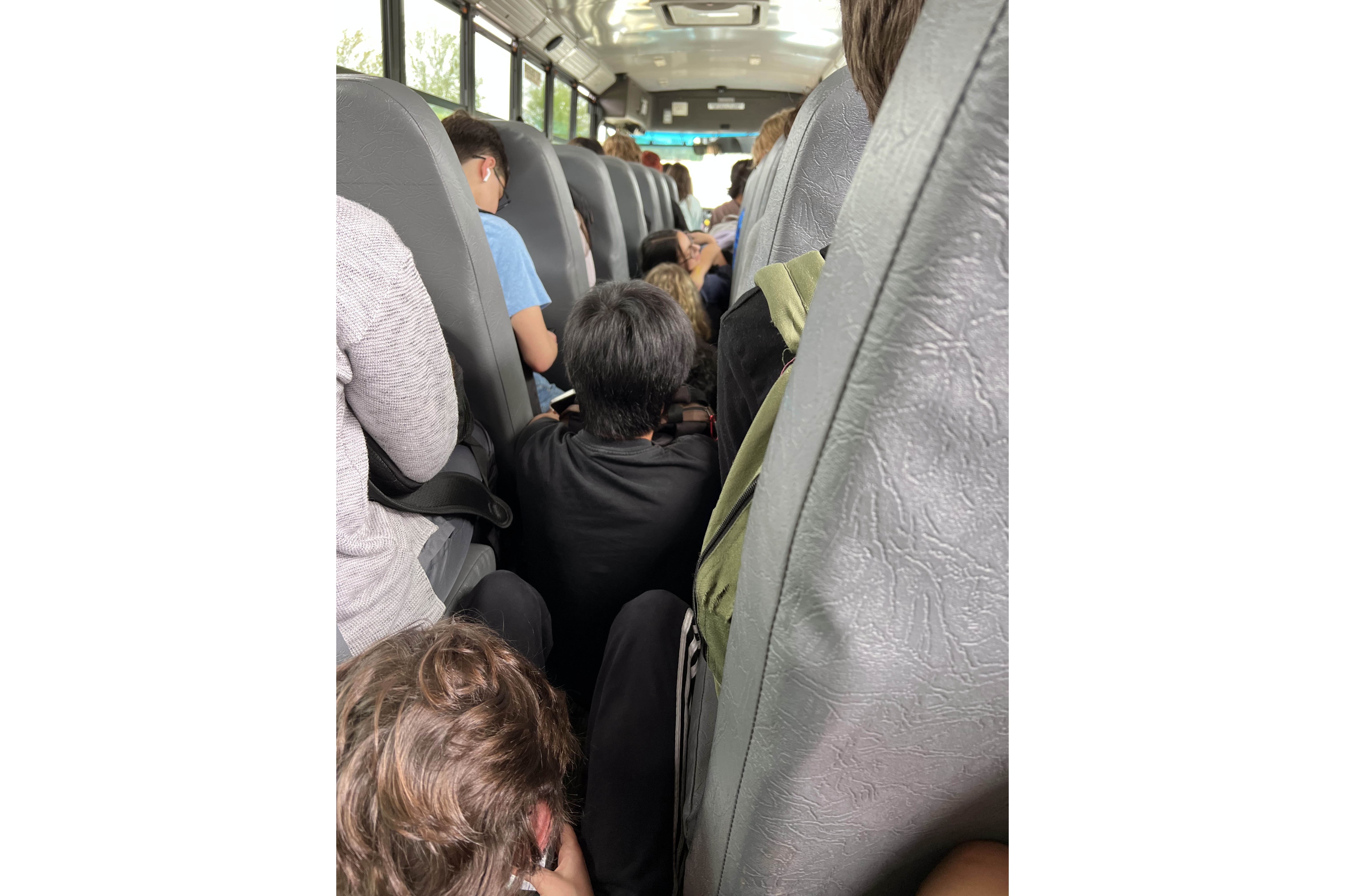 A cell phone image showing students sitting in the aisle of an MCCSC school bus.