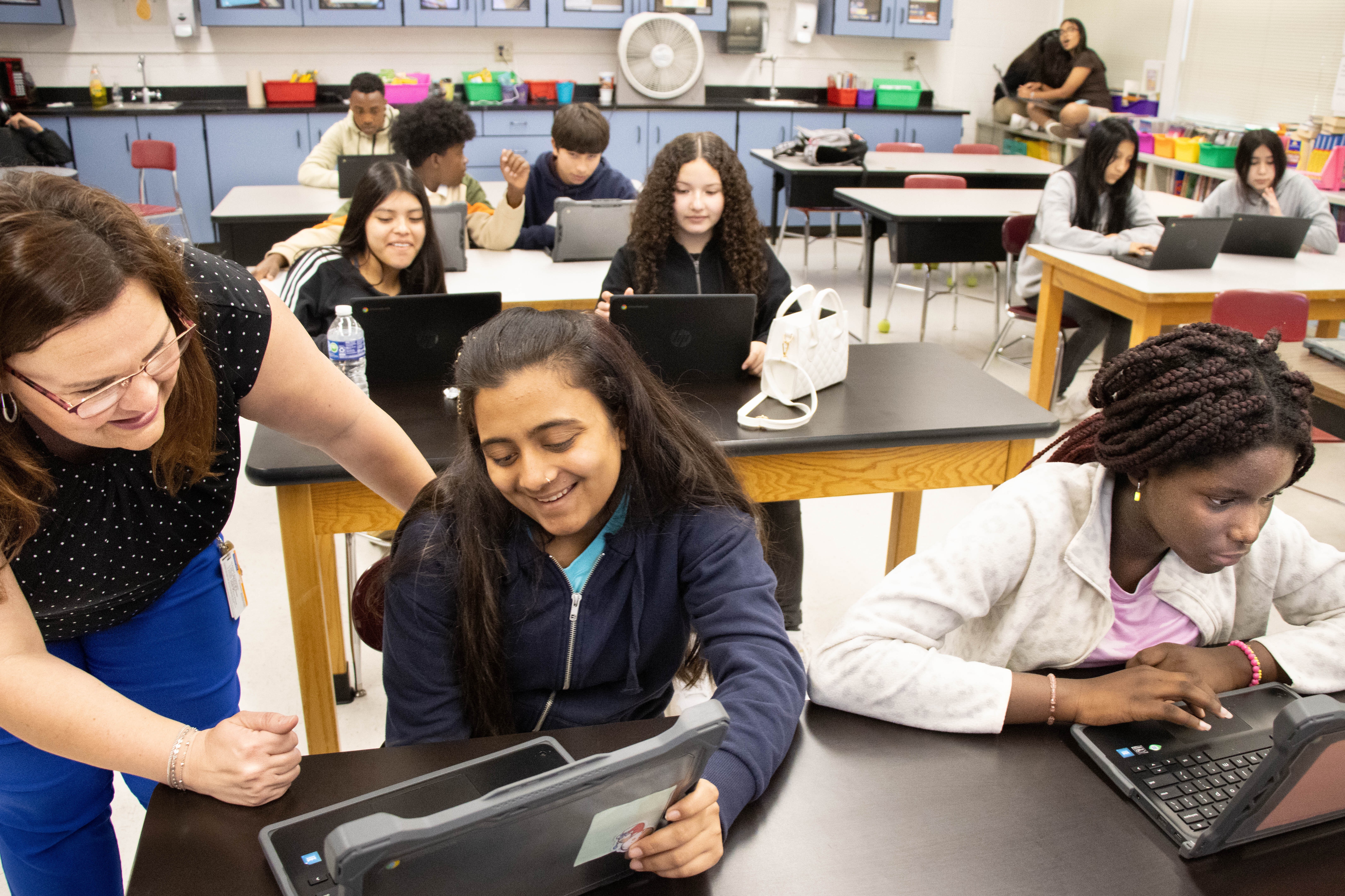 EVSC ESL teacher Susan Riordan looks at slides by Feniben Chaudhari, contrasting her home country of India to the United States. This class is part of the International Newcomers Academy.